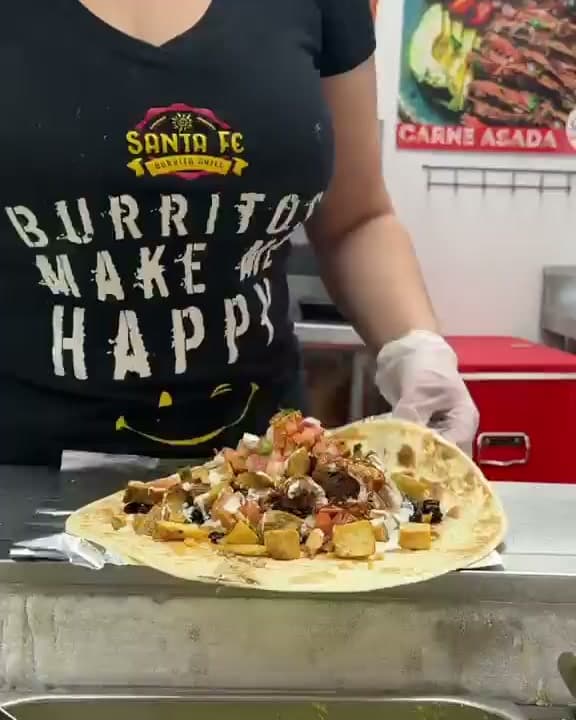 A Santa Fe crew member in a “Burritos make me happy” shirt wrapping a burrito at the line