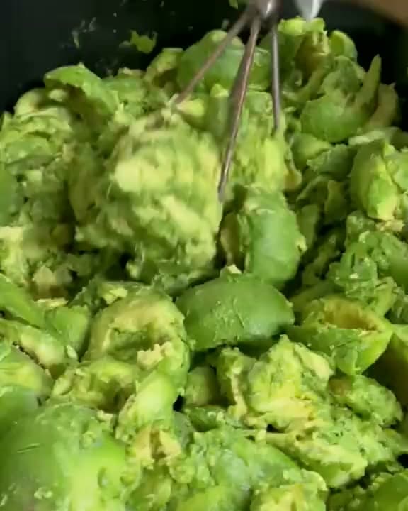 Gloved hands mashing fresh avocados into guacamole in the Santa Fe kitchen