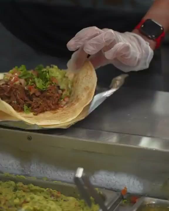 A Santa Fe cook folding a loaded burrito at the line